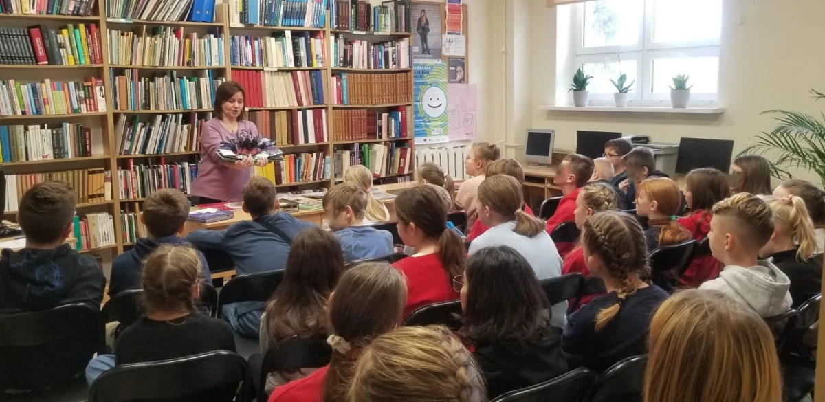 Prowadząca i uczestnicy lekcji bibliotecznej.